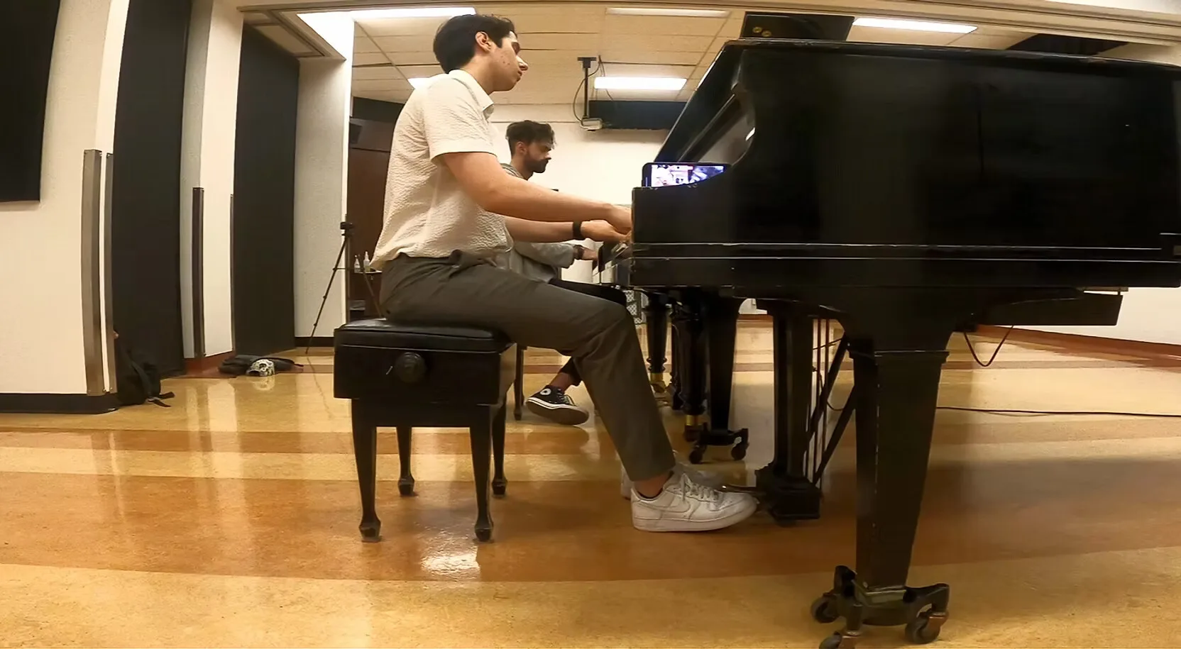 Mircea au piano à queue aux côtés d'un collègue musicien.